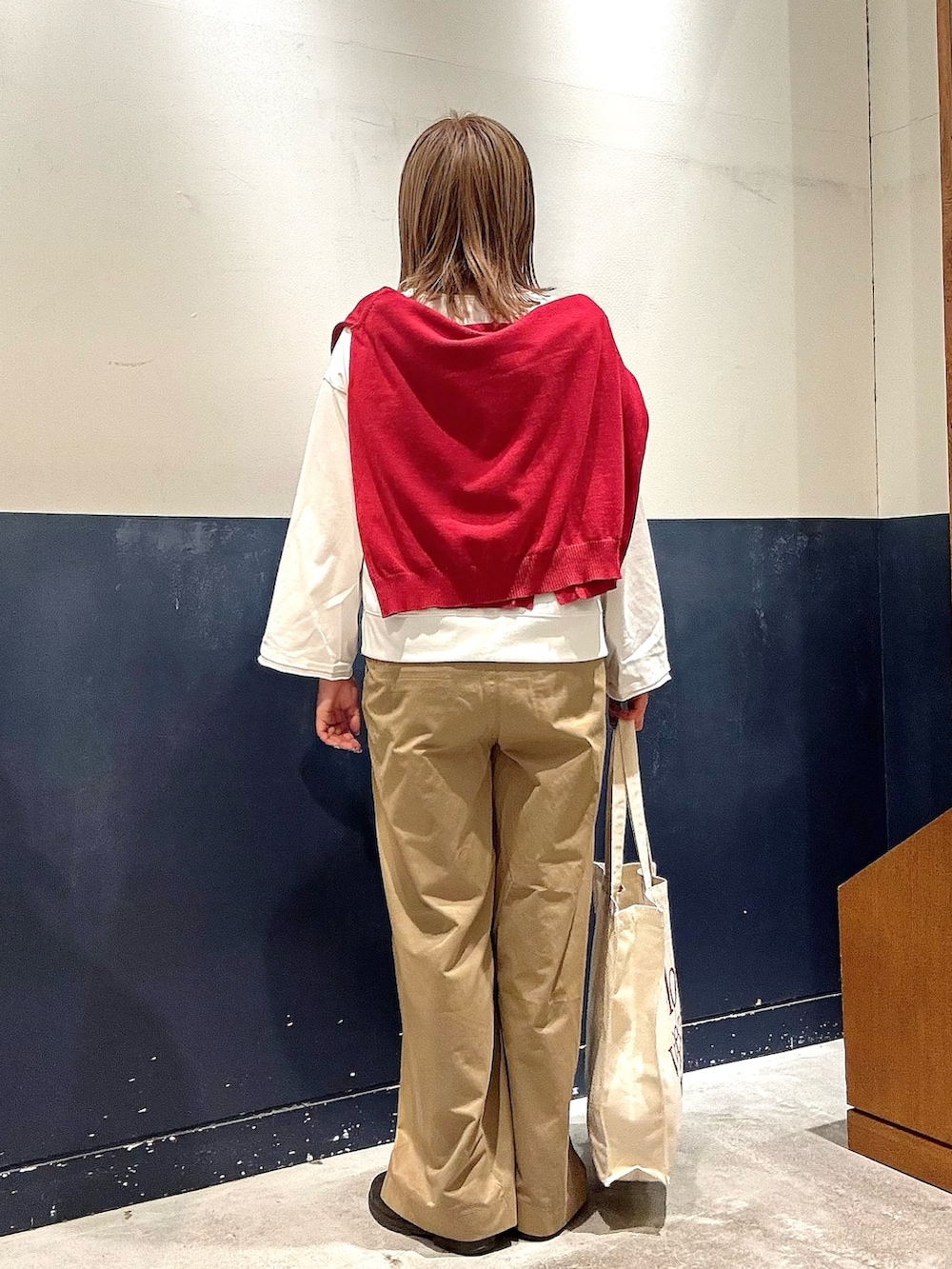 レッド系のニット/セーター、ホワイト系のTシャツ/カットソー、ベージュ系のデニムパンツを着用したレディースの冬コーディネートの3枚目の写真