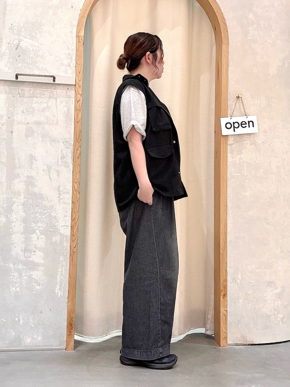ブラック系のデニムパンツ、ブラック系のベスト、グレー系のTシャツ/カットソーを着用したレディースの夏コーディネートの2枚目の写真