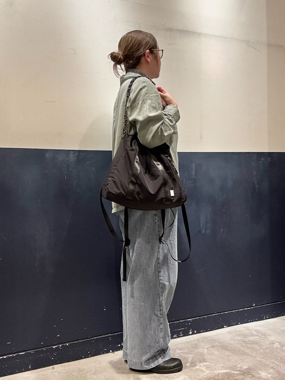 グリーン系のシャツ/ブラウス、ブラック系のトートバッグ、ブルー系のデニムパンツを着用したレディースの冬コーディネートの2枚目の写真