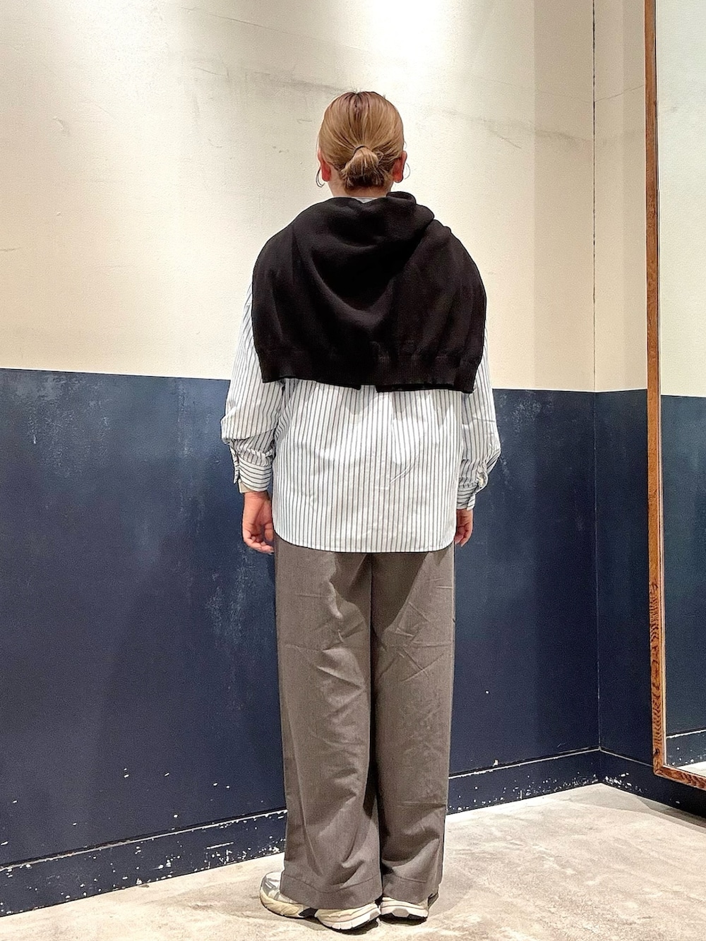 グレー系のデニムパンツ、ブルー系のシャツ/ブラウス、ブラック系のニット/セーターを着用したレディースの春コーディネートの3枚目の写真