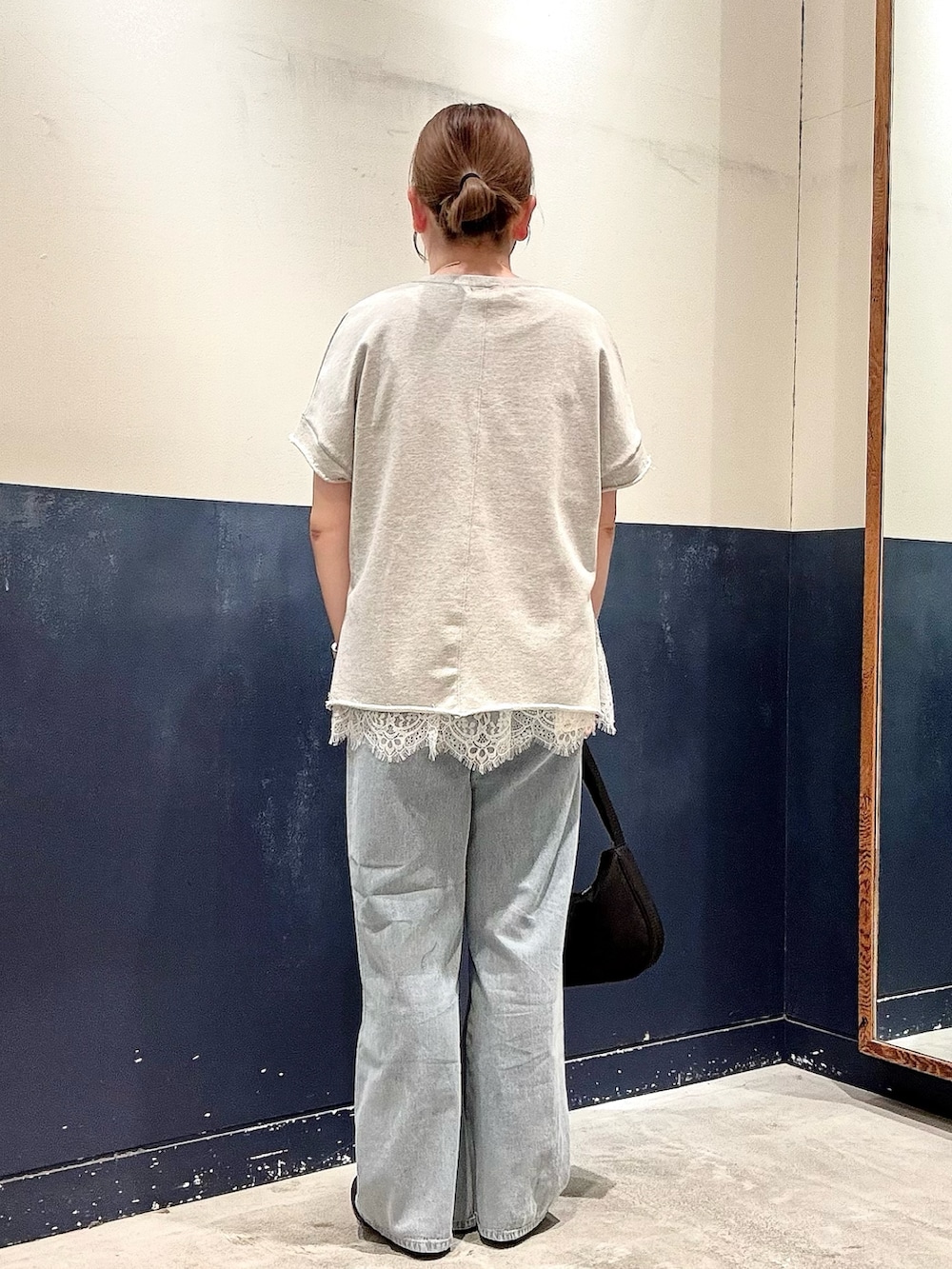 ブルー系のデニムパンツ、ブラック系のショルダーバッグ、ブラック系のスニーカーを着用したレディースの春コーディネートの3枚目の写真