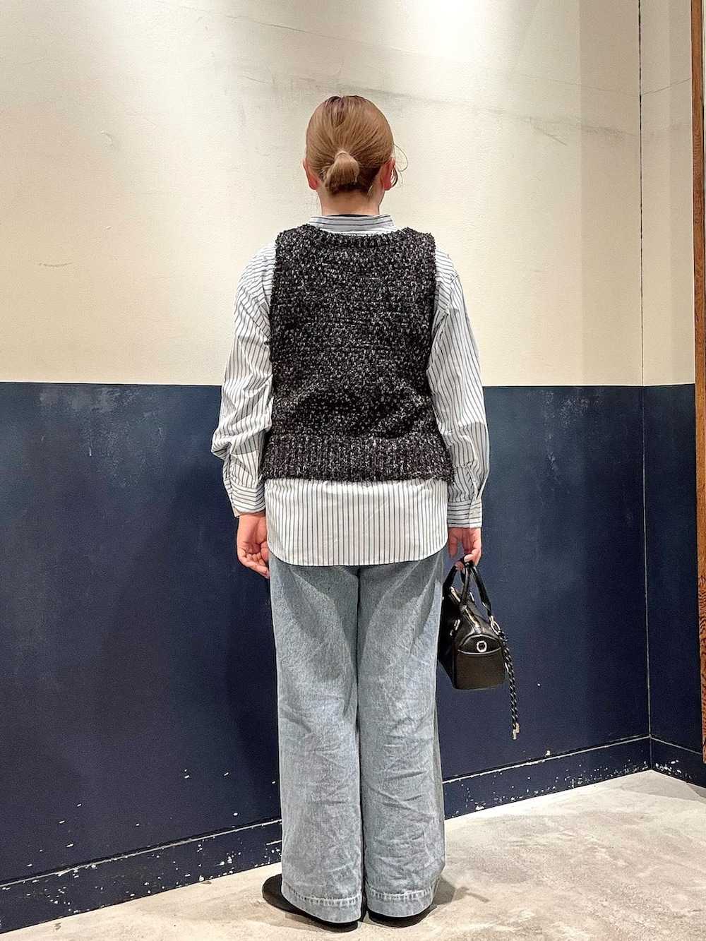 ブルー系のデニムパンツ、ブラック系のショルダーバッグ、ブラック系のベストを着用したレディースの冬コーディネートの3枚目の写真