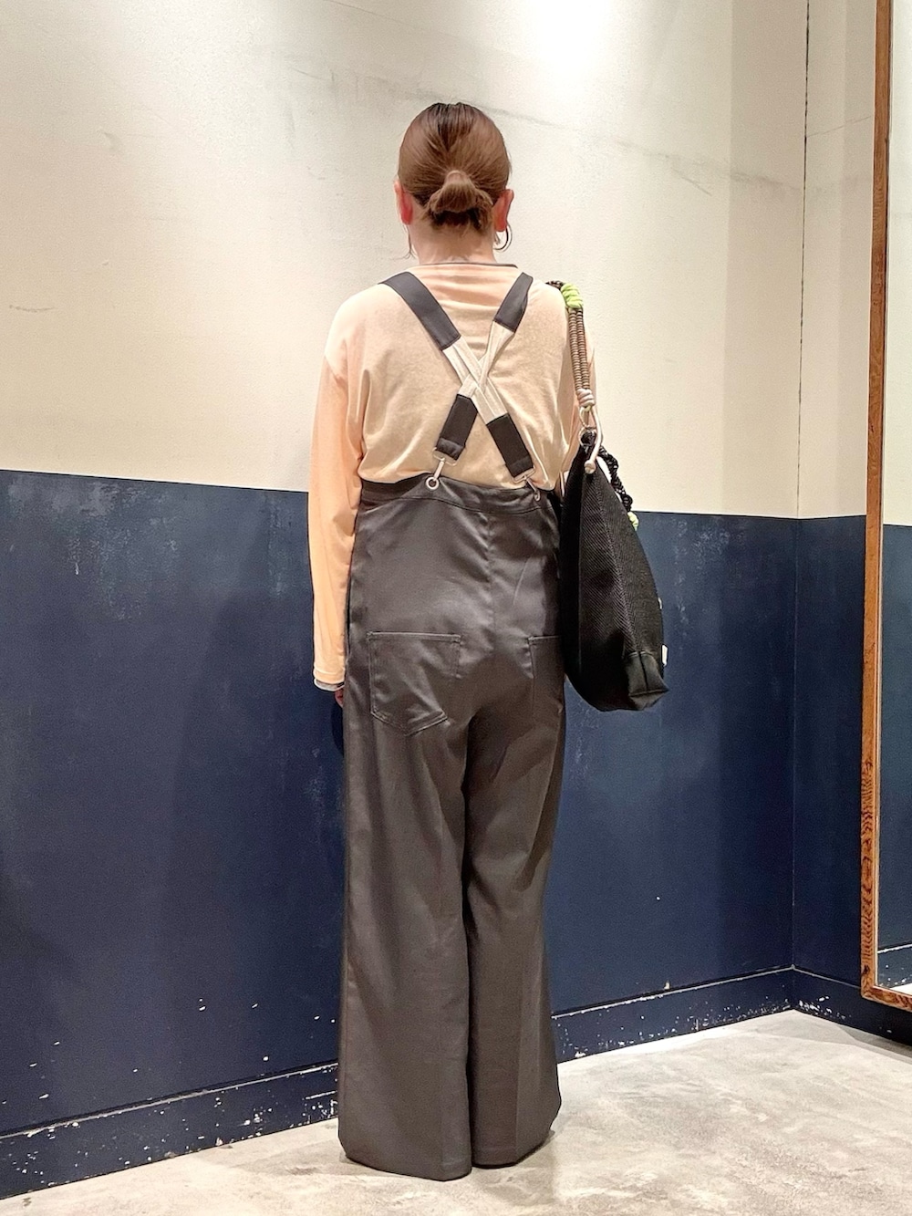 ブラック系のショルダーバッグ、グレー系のサロペット/オーバーオール、オレンジ系のTシャツ/カットソーを着用したレディースの春コーディネートの3枚目の写真