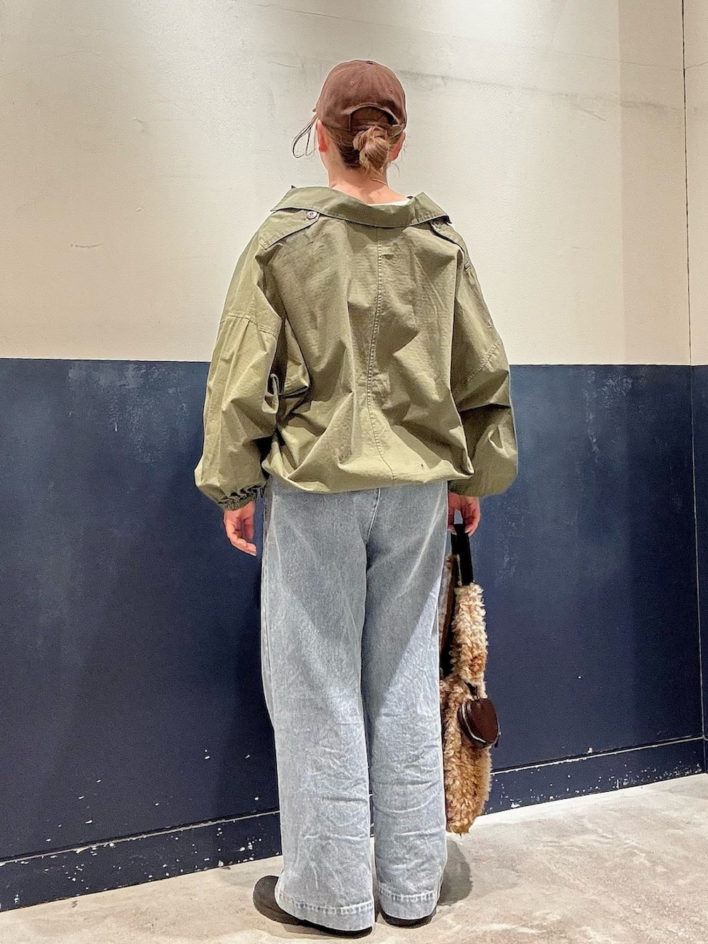 ベージュ系のトートバッグ、ホワイト系のTシャツ/カットソー、グリーン系のブルゾンを着用したレディースの冬コーディネートの3枚目の写真