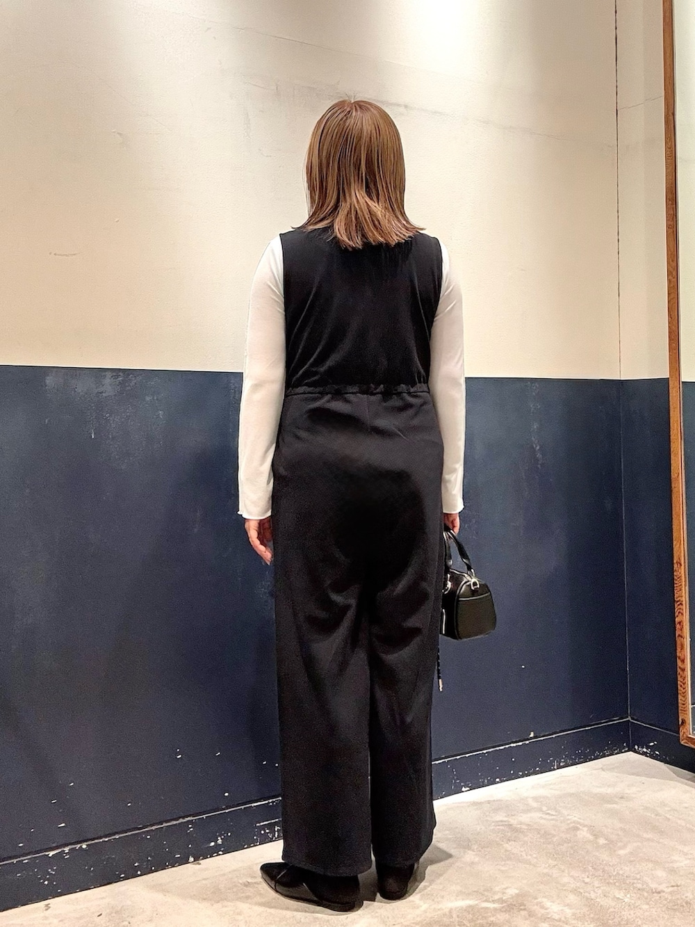 ブルー系のサロペット/オーバーオール、ブラック系のパンプス、ブラック系のショルダーバッグを着用したレディースの冬コーディネートの3枚目の写真