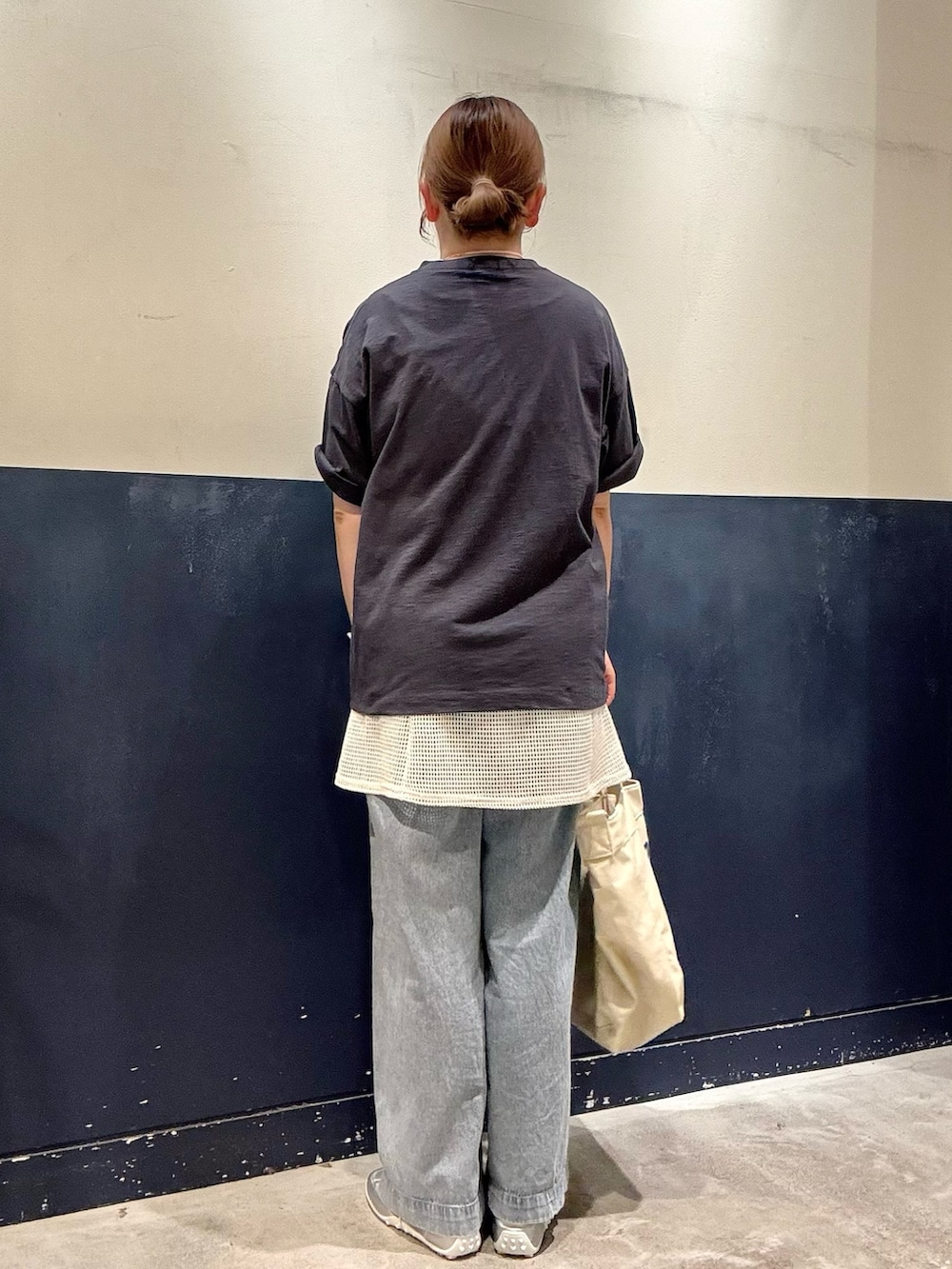シルバー系のスニーカー、ブルー系のデニムパンツ、ホワイト系のショルダーバッグを着用したレディースの春コーディネートの3枚目の写真