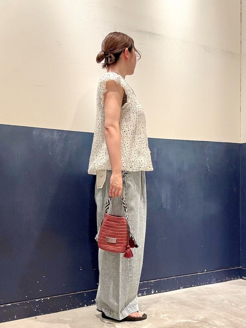 レッド系のトートバッグ、ブルー系のデニムパンツ、ホワイト系のシャツ/ブラウスを着用したレディースの夏コーディネートの2枚目の写真