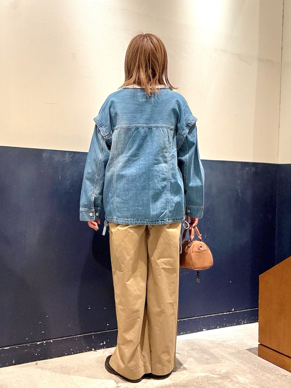 ベージュ系のショルダーバッグ、ブルー系のデニムジャケット、ベージュ系のデニムパンツを着用したレディースの冬コーディネートの3枚目の写真