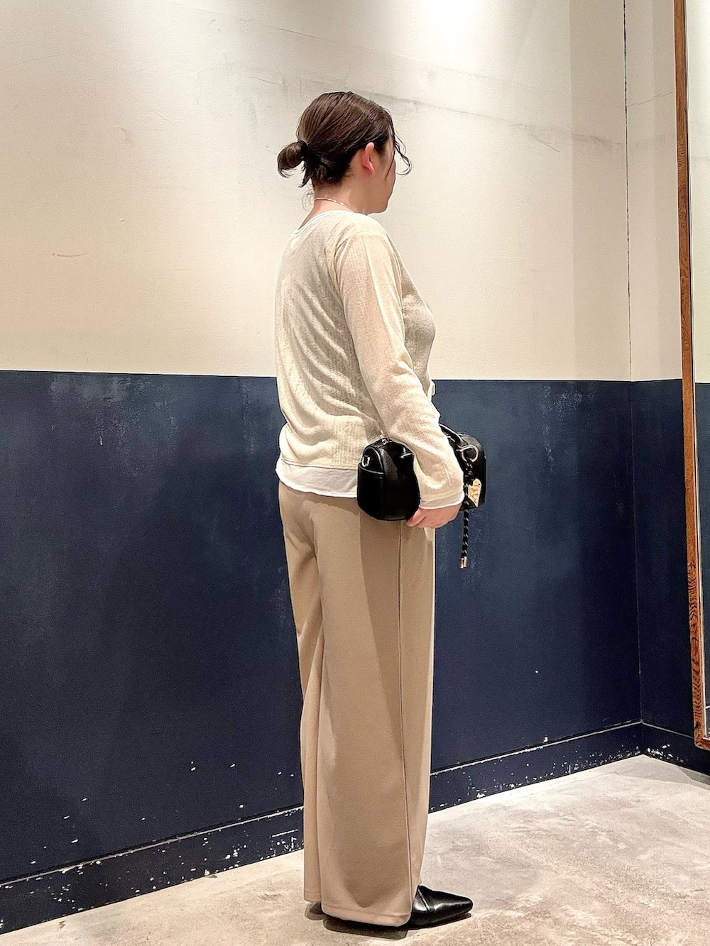 ブラック系のパンプス、ブラック系のショルダーバッグ、イエロー系のカーディガン/ボレロを着用したレディースの春コーディネートの2枚目の写真