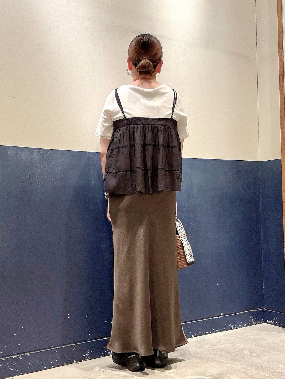 グレー系のスカート、ブラウン系のトートバッグ、ブラック系のシャツ/ブラウスを着用したレディースの夏コーディネートの3枚目の写真