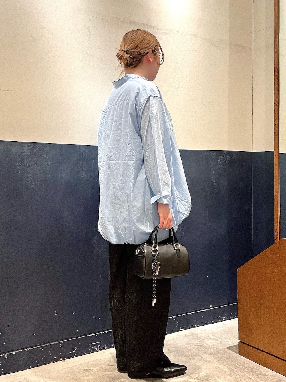 ブラック系のパンプス、ブルー系のシャツ/ブラウス、ブラック系のショルダーバッグを着用したレディースの春コーディネートの2枚目の写真