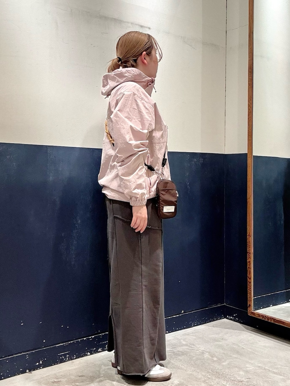 グレー系のスカート、ブラウン系のショルダーバッグ、ピンク系のマウンテンパーカーを着用したレディースの春コーディネートの2枚目の写真