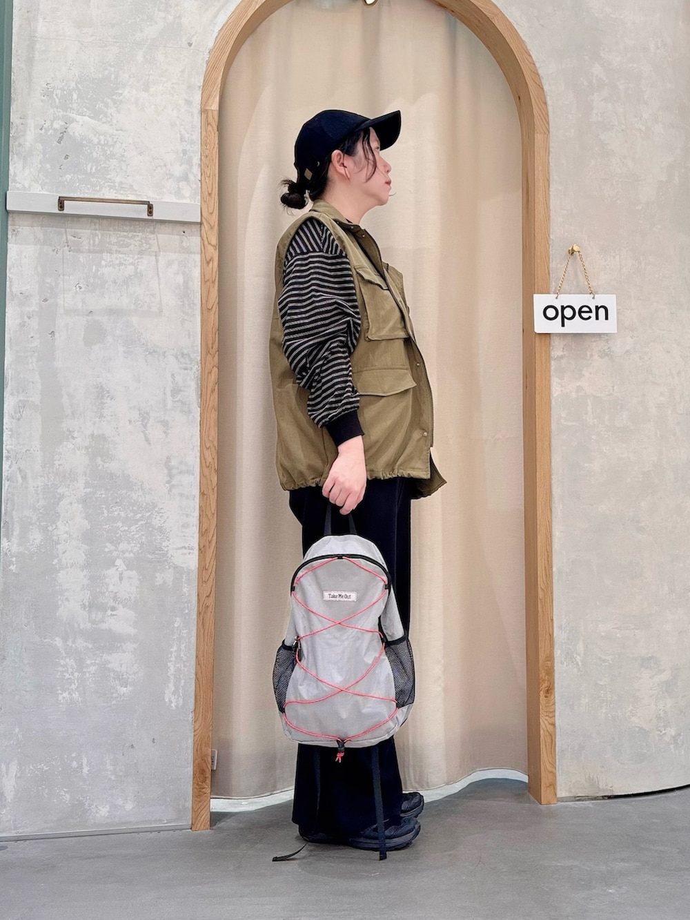 グレー系のバックパック/リュック、ブラック系のその他パンツ、グリーン系のベストを着用したレディースの秋コーディネートの2枚目の写真
