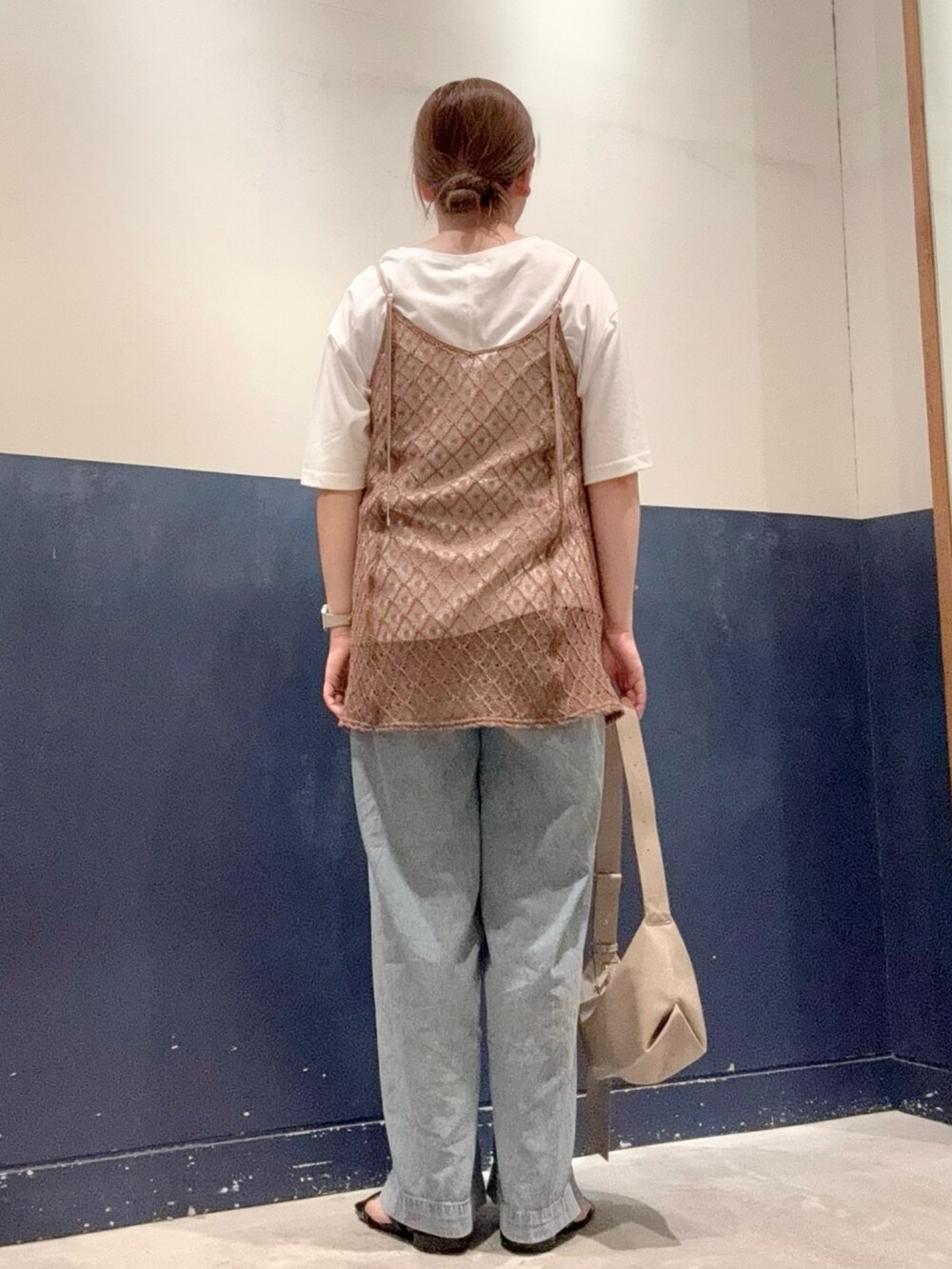 ブルー系のデニムパンツ、ブラック系のサンダル、ホワイト系のTシャツ/カットソーを着用したレディースの夏コーディネートの3枚目の写真