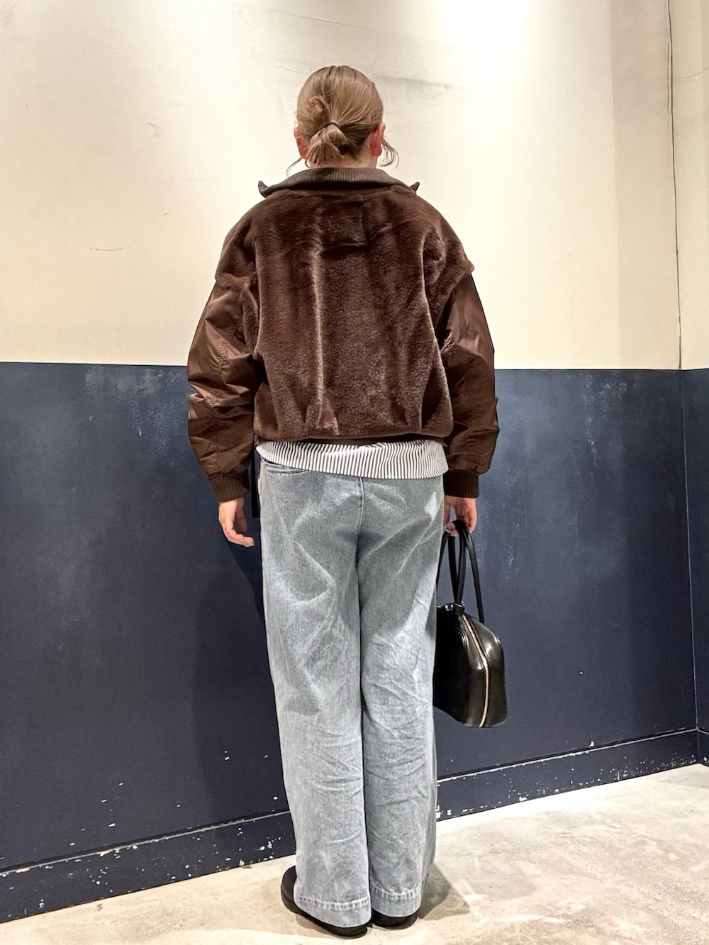 ブルー系のデニムパンツ、ブラック系のボストンバッグ、ブラウン系のブルゾンを着用したレディースの冬コーディネートの3枚目の写真