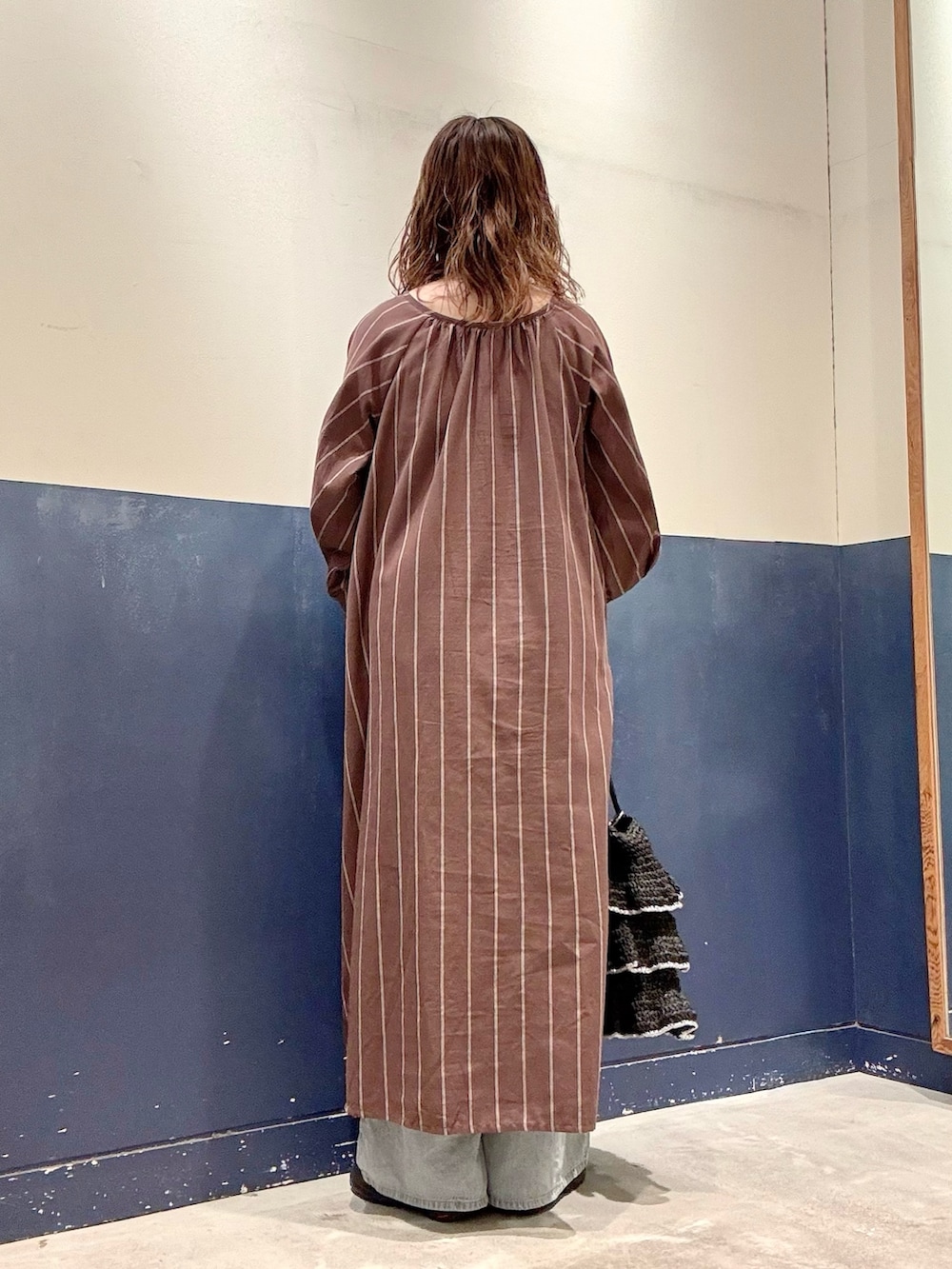 ブラウン系のワンピース、ブラック系のトートバッグ、ブルー系のデニムパンツを着用したレディースの夏コーディネートの3枚目の写真