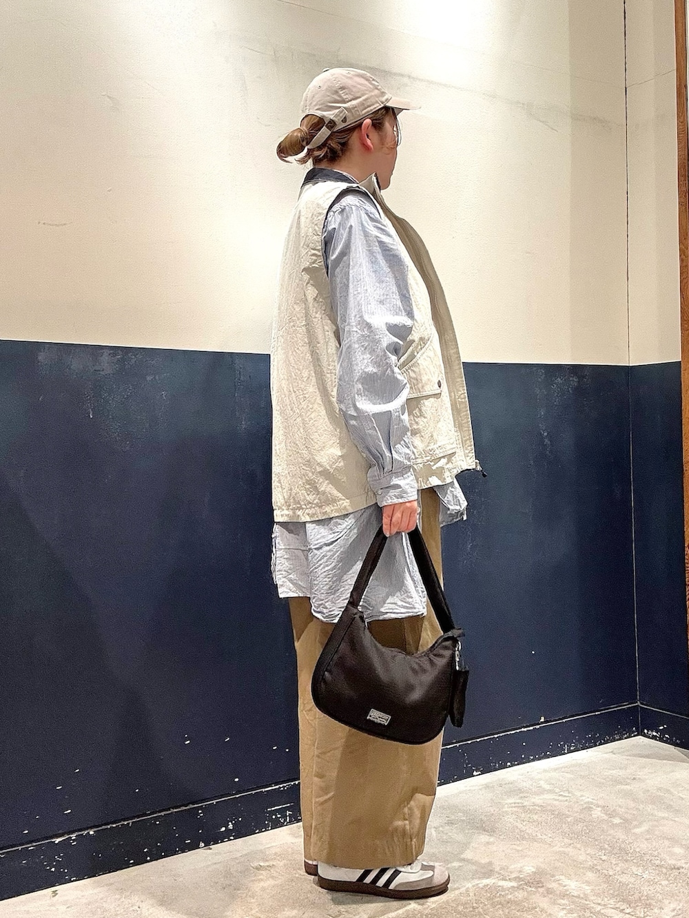 グレー系のベスト、ブルー系のシャツ/ブラウス、ブラック系のショルダーバッグを着用したレディースの春コーディネートの2枚目の写真