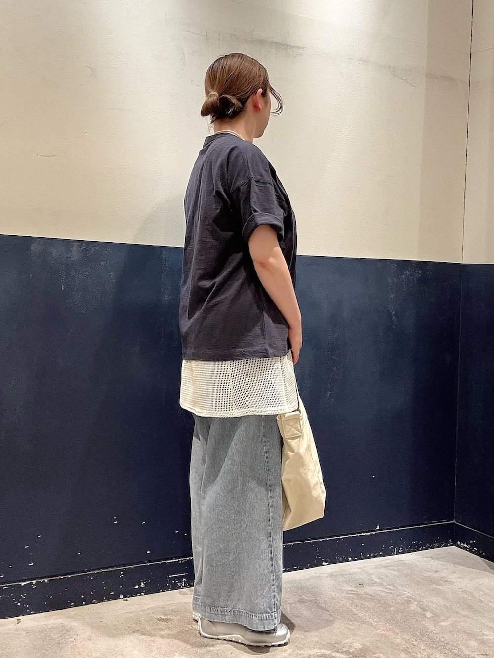 シルバー系のスニーカー、ブルー系のデニムパンツ、ホワイト系のショルダーバッグを着用したレディースの春コーディネートの2枚目の写真