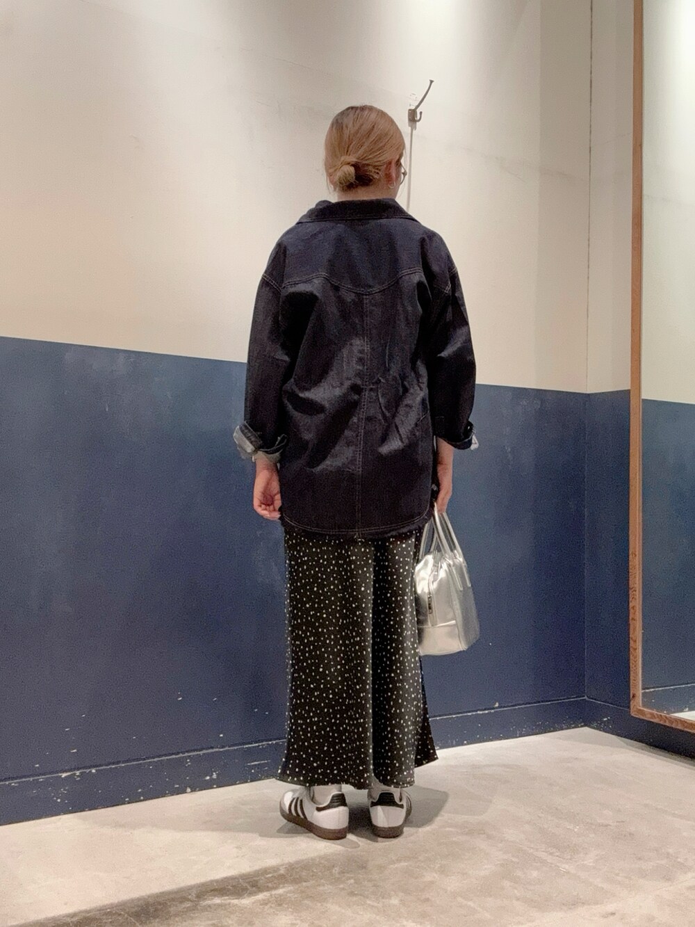 ブラック系のスカート、シルバー系のボストンバッグ、ブルー系のデニムジャケットを着用したレディースの春コーディネートの3枚目の写真