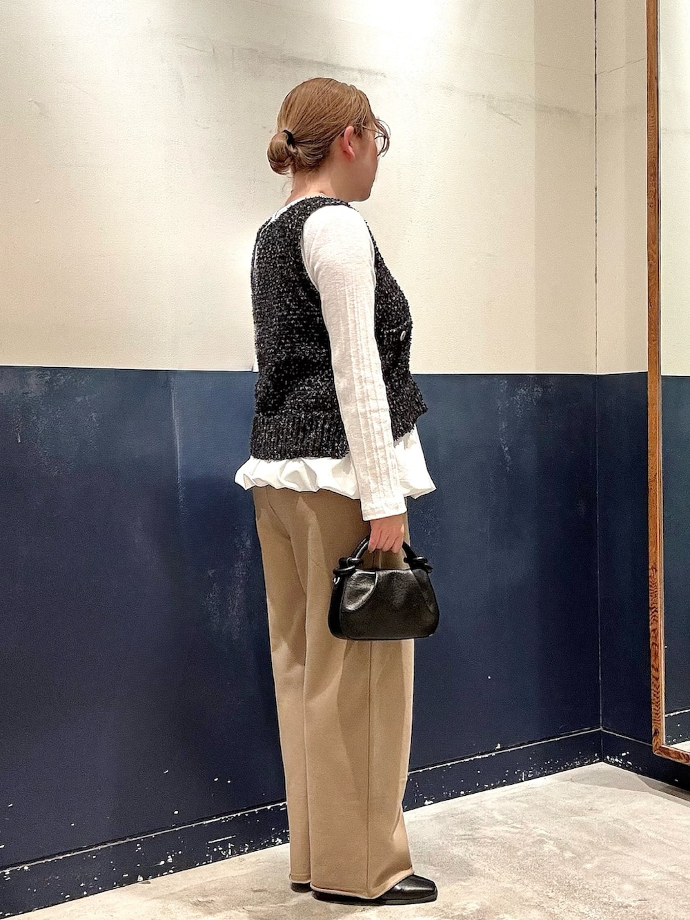 ホワイト系のTシャツ/カットソー、ブラック系のベスト、ブラック系のショルダーバッグを着用したレディースの冬コーディネートの2枚目の写真