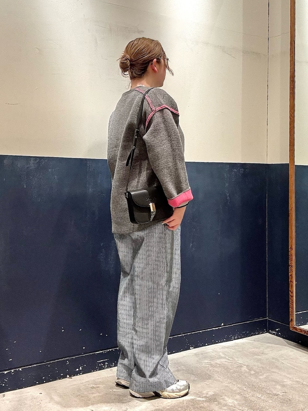 グレー系のカーディガン/ボレロ、ブルー系のデニムパンツ、ブラック系のショルダーバッグを着用したレディースの冬コーディネートの2枚目の写真