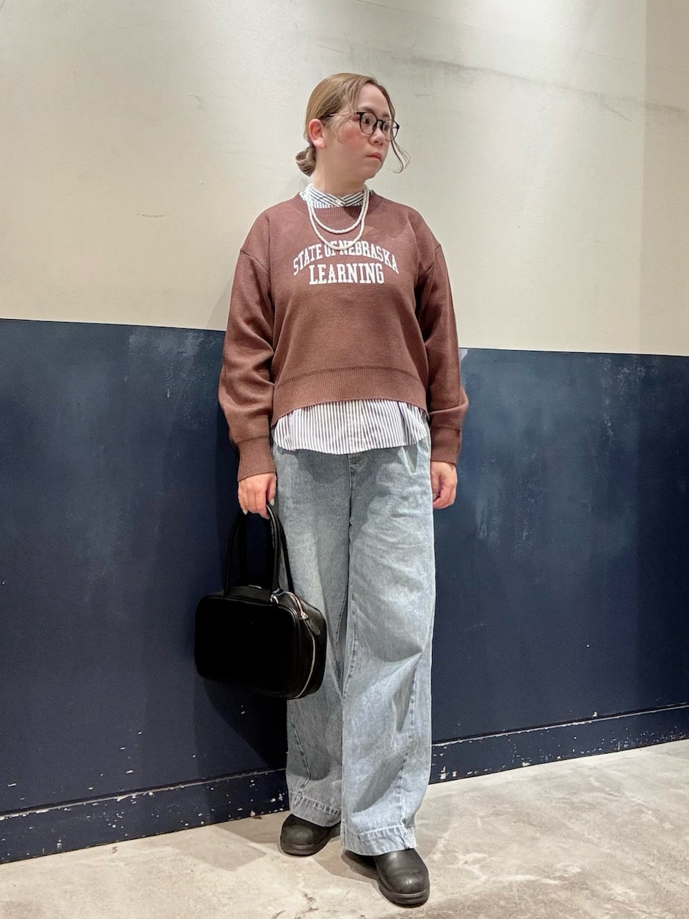 ブルー系のデニムパンツ、ブラック系のボストンバッグ、ブラウン系のブルゾンを着用したレディースの冬コーディネートの4枚目の写真