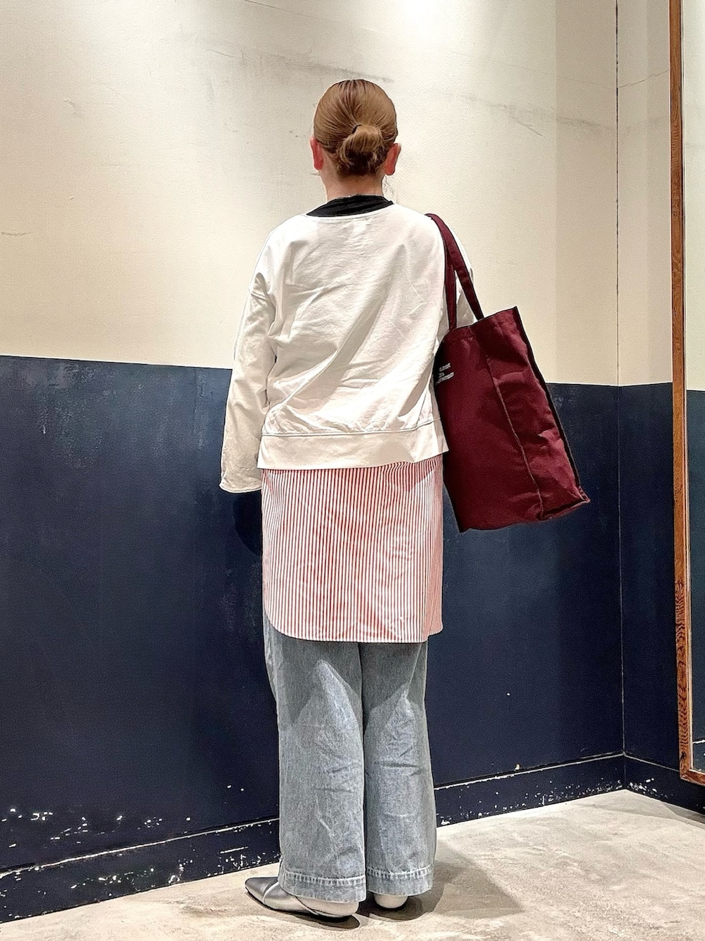 シルバー系のパンプス、ブルー系のデニムパンツ、ブラウン系のトートバッグを着用したレディースの冬コーディネートの3枚目の写真