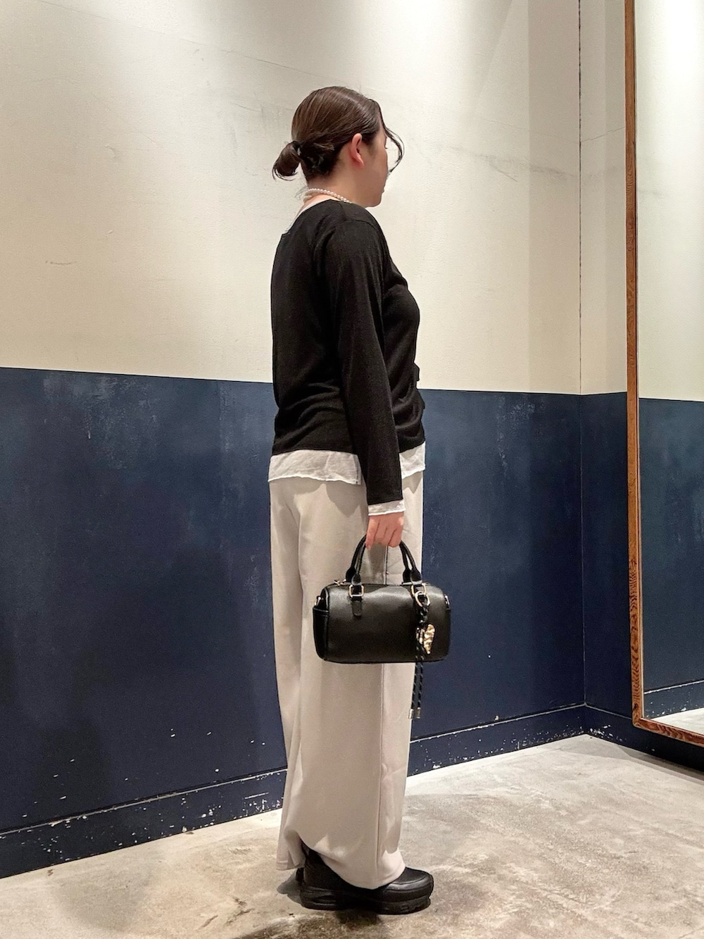 グレー系のスラックス、ブラック系のショルダーバッグ、ブラック系のカーディガン/ボレロを着用したレディースの春コーディネートの2枚目の写真