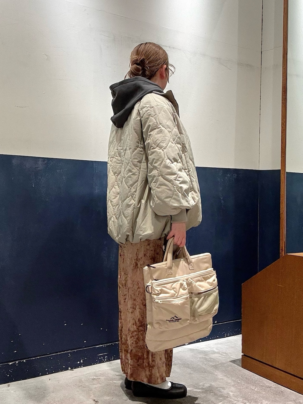 グリーン系のブルゾン、グレー系のTシャツ/カットソー、ベージュ系のショルダーバッグを着用したレディースの冬コーディネートの2枚目の写真