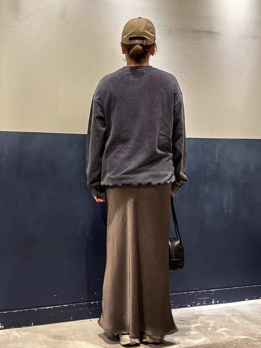 グレー系のスカート、ブラック系のトートバッグ、ブルー系のスウェットを着用したレディースの秋コーディネートの4枚目の写真