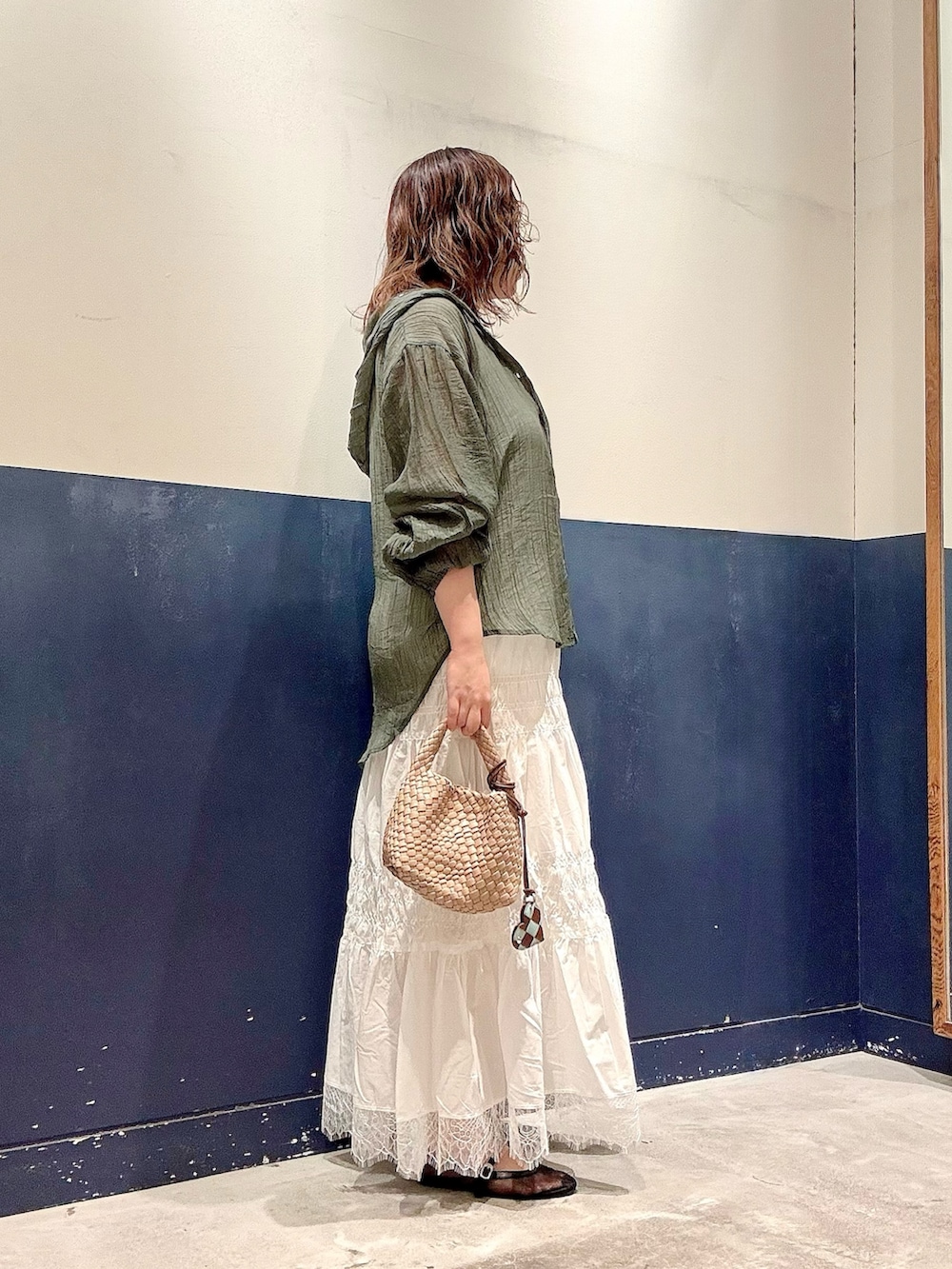 ブラック系のパンプス、ベージュ系のショルダーバッグ、ホワイト系のスカートを着用したレディースの夏コーディネートの2枚目の写真