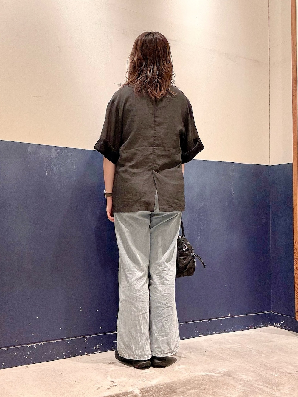 ブラック系のショルダーバッグ、ブルー系のデニムパンツ、ブラック系のテーラードジャケットを着用したレディースの夏コーディネートの3枚目の写真