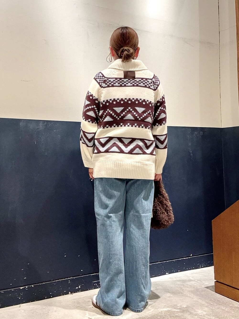 ブラウン系のトートバッグ、ブルー系のデニムパンツ、ホワイト系のカーディガン/ボレロを着用したレディースの秋コーディネートの3枚目の写真