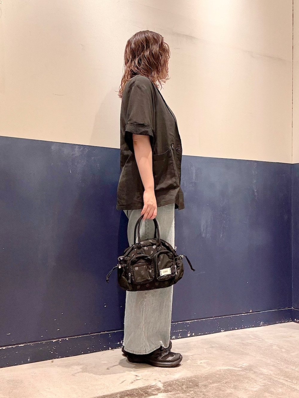ブラック系のショルダーバッグ、ブルー系のデニムパンツ、ブラック系のテーラードジャケットを着用したレディースの夏コーディネートの2枚目の写真