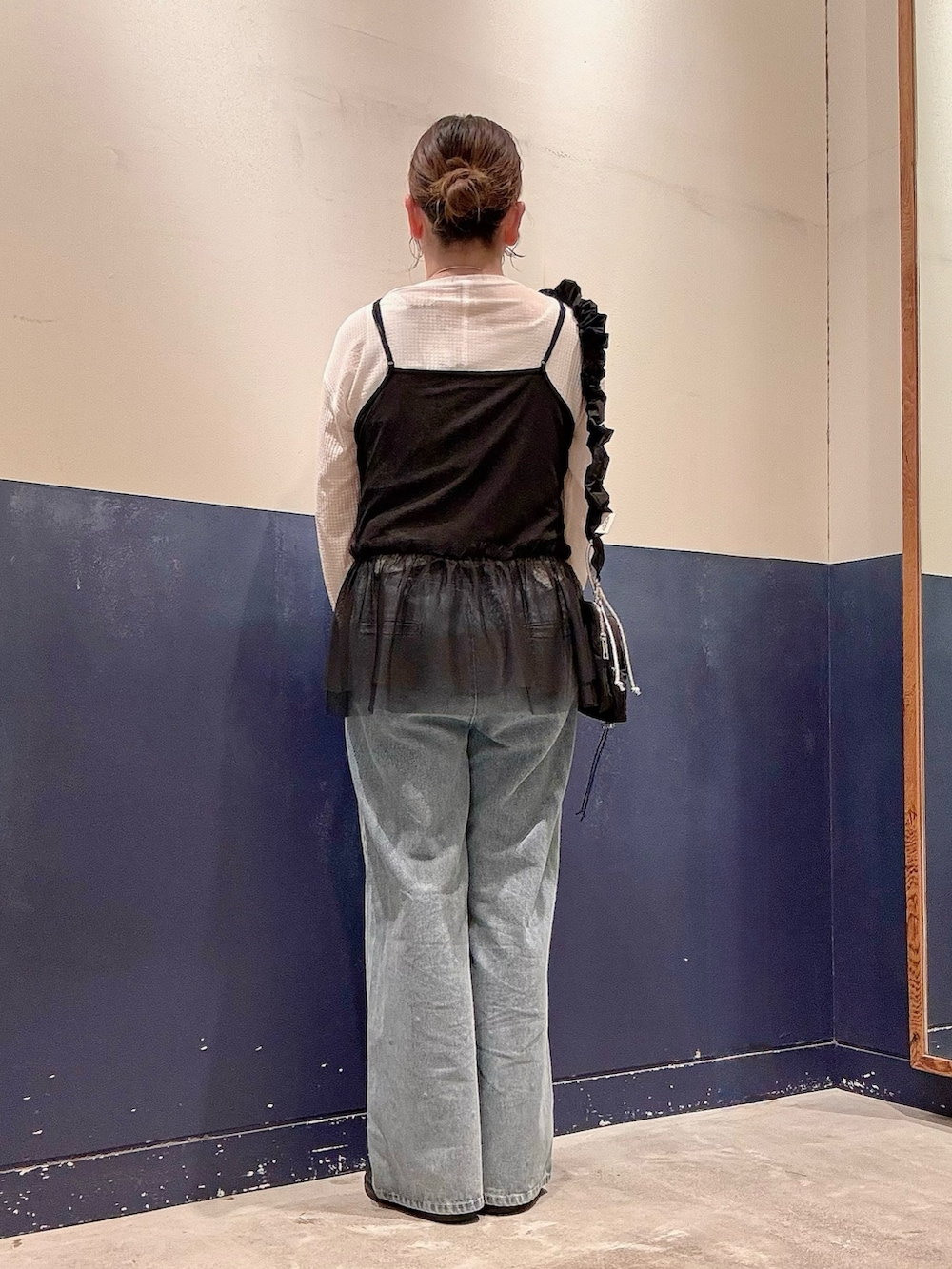 ブルー系のデニムパンツ、ブラック系のキャミソール、ブラック系のショルダーバッグを着用したレディースの秋コーディネートの3枚目の写真