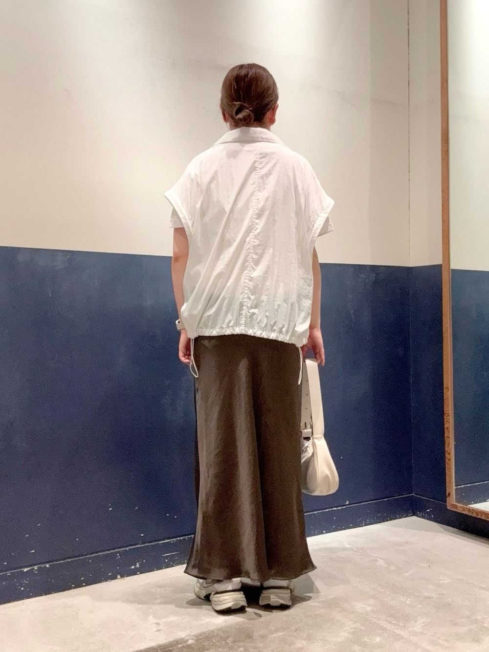 グレー系のスカート、ホワイト系のナイロンジャケット、グレー系のTシャツ/カットソーを着用したレディースの夏コーディネートの3枚目の写真