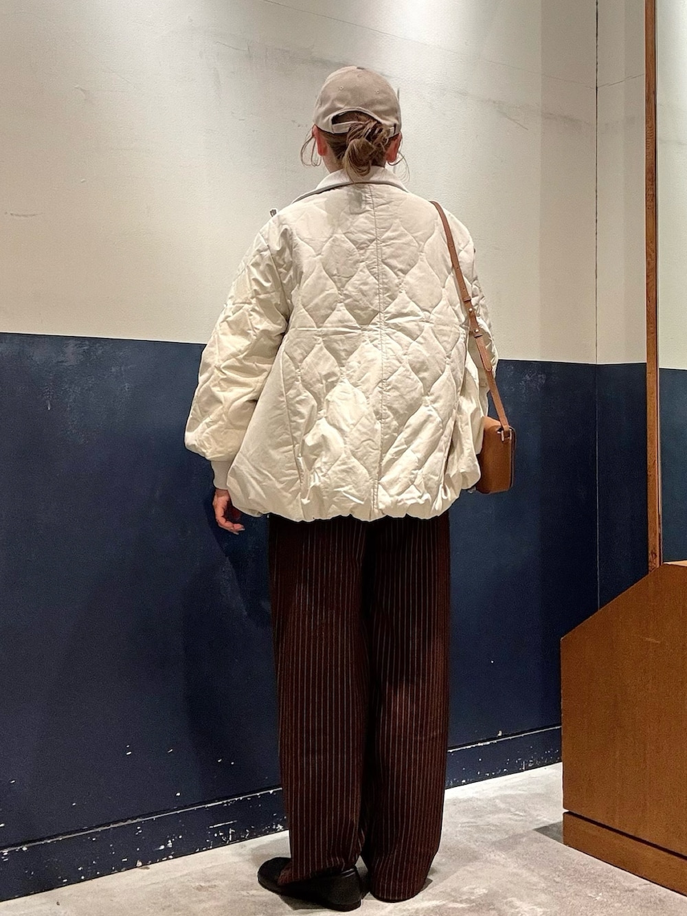 ホワイト系のブルゾン、ブラウン系のスラックス、イエロー系のショルダーバッグを着用したレディースの冬コーディネートの3枚目の写真