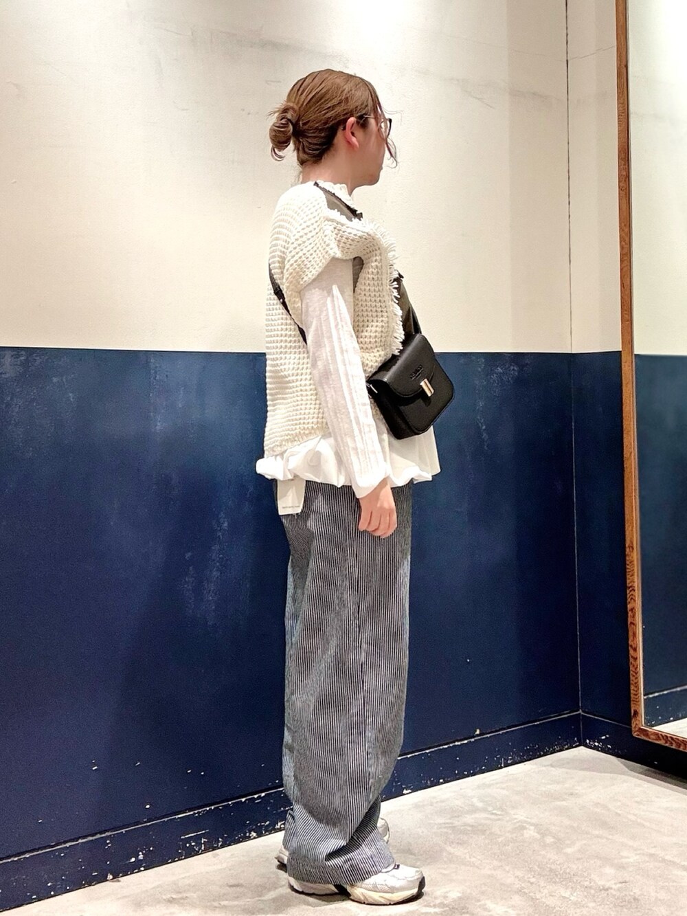 グリーン系のニット/セーター、ブルー系のデニムパンツ、ブラック系のショルダーバッグを着用したレディースの冬コーディネートの2枚目の写真