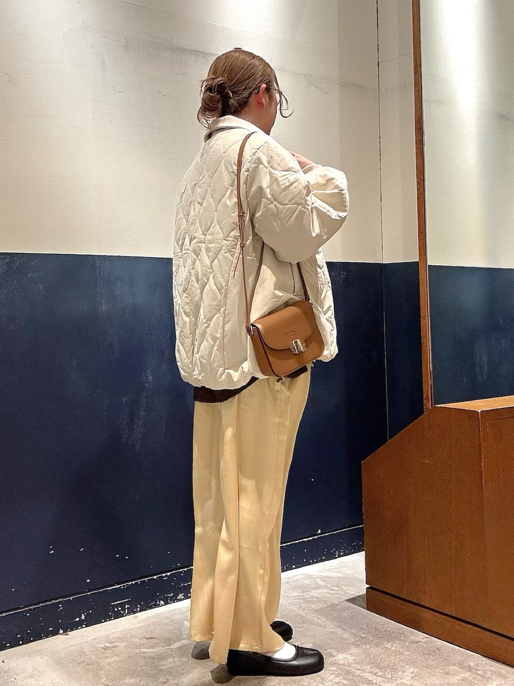 ホワイト系のブルゾン、ブラウン系のニット/セーター、イエロー系のショルダーバッグを着用したレディースの冬コーディネートの2枚目の写真