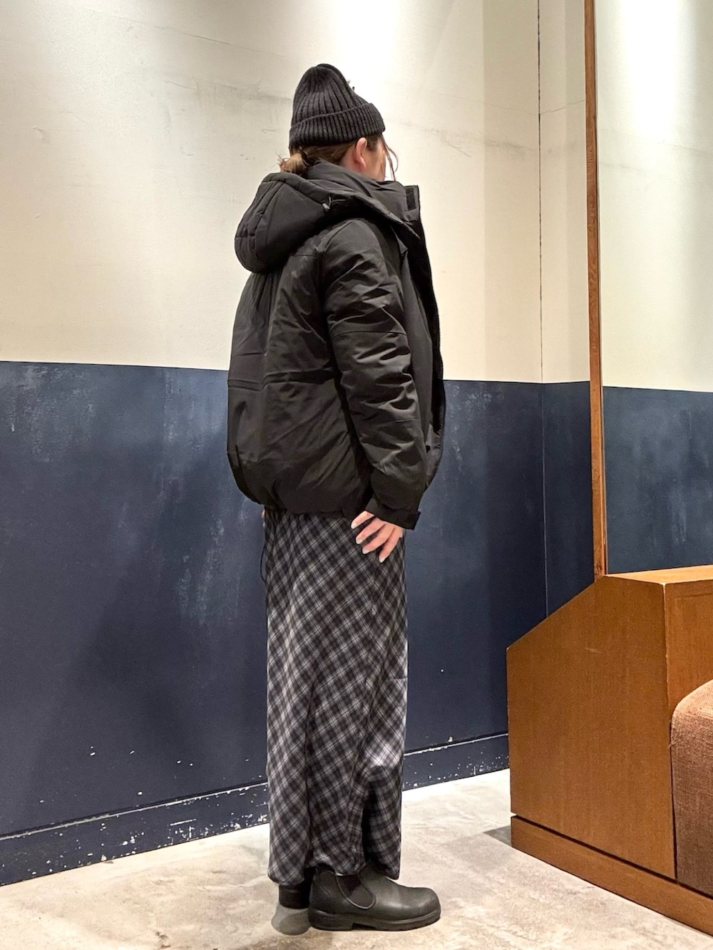 グレー系のスカート、グレー系のニット/セーター、ブラック系のダウンジャケット/コートを着用したレディースの冬コーディネートの2枚目の写真