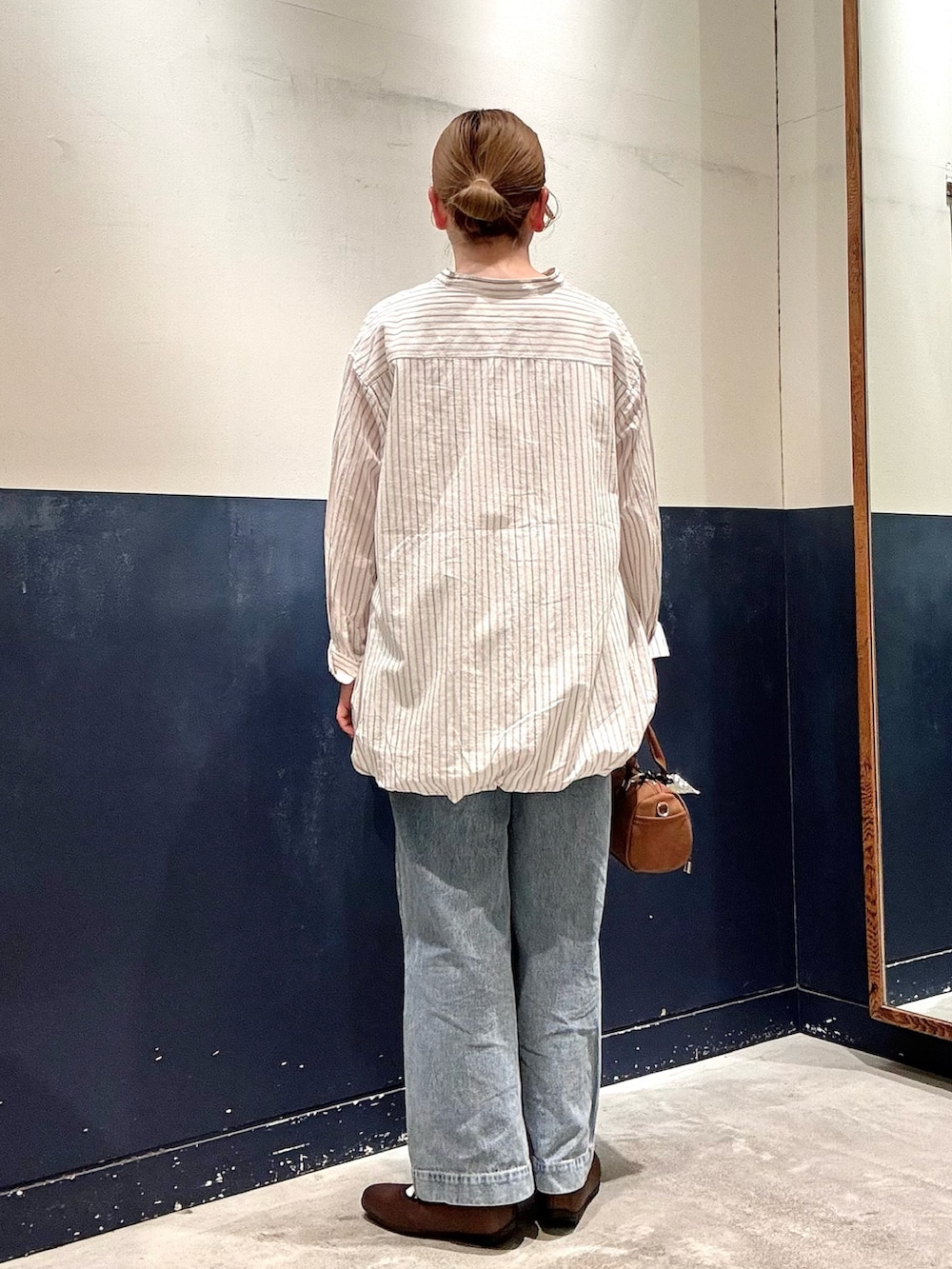 ブルー系のデニムパンツ、ベージュ系のショルダーバッグ、ホワイト系のシャツ/ブラウスを着用したレディースの春コーディネートの3枚目の写真