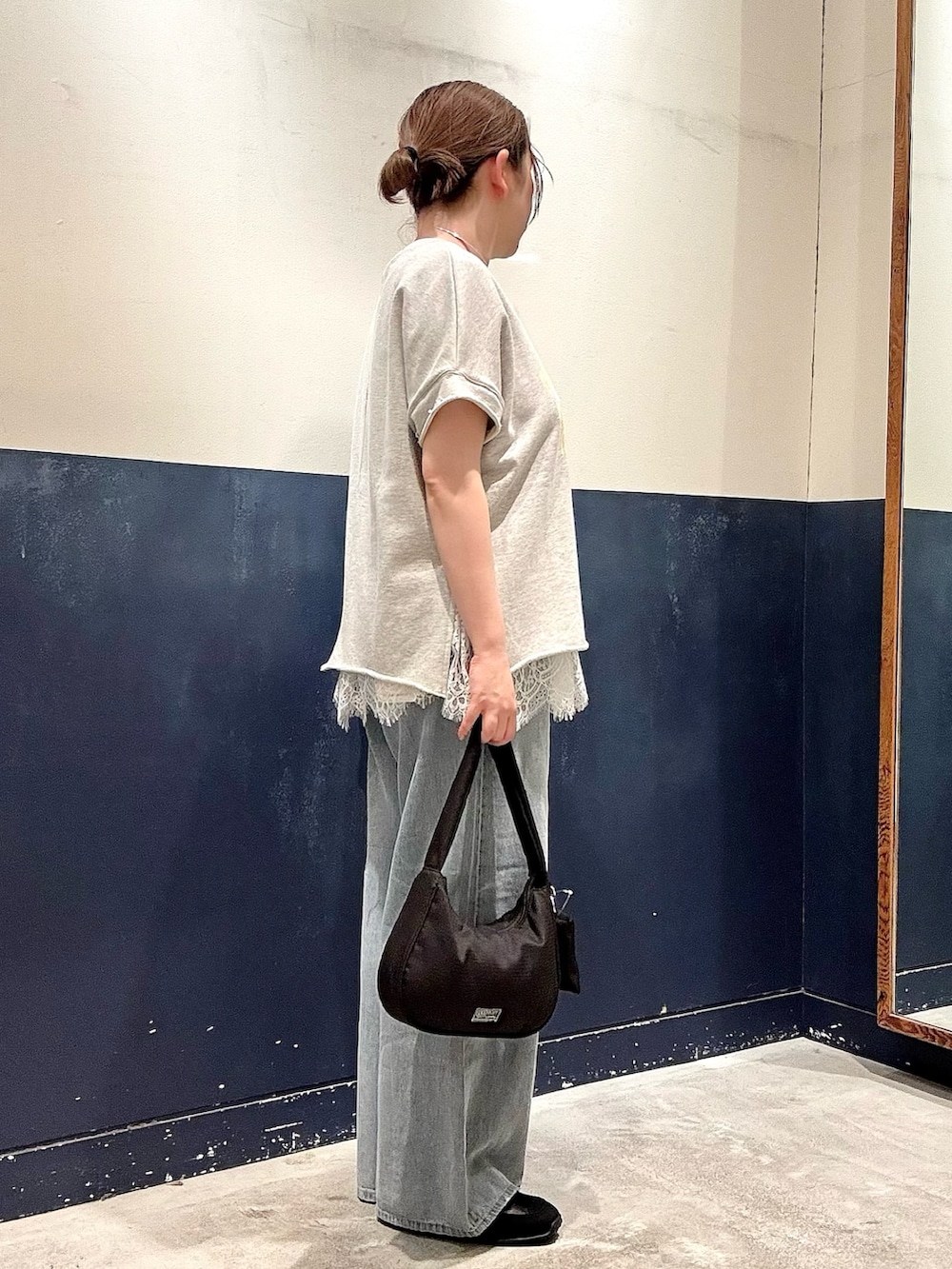 ブルー系のデニムパンツ、ブラック系のショルダーバッグ、ブラック系のスニーカーを着用したレディースの春コーディネートの2枚目の写真
