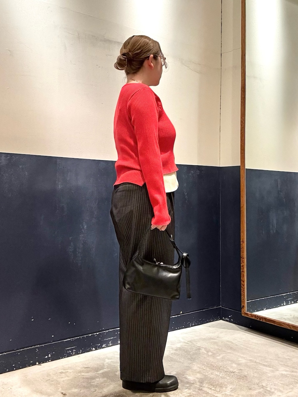 グレー系のスラックス、ブラック系のショルダーバッグ、レッド系のカーディガン/ボレロを着用したレディースの冬コーディネートの2枚目の写真