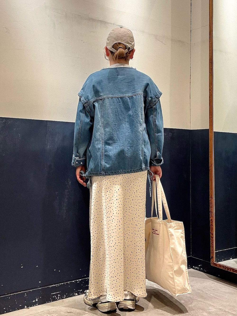 グレー系のニット/セーター、ブルー系のデニムジャケット、ホワイト系のスカートを着用したレディースの春コーディネートの3枚目の写真