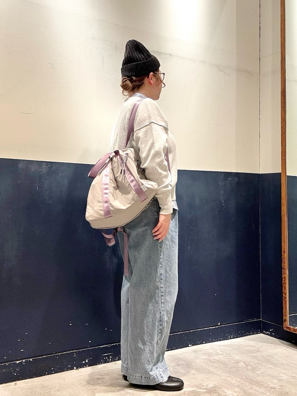 ブルー系のデニムパンツ、グレー系のトートバッグ、ホワイト系のニット/セーターを着用したレディースの冬コーディネートの2枚目の写真