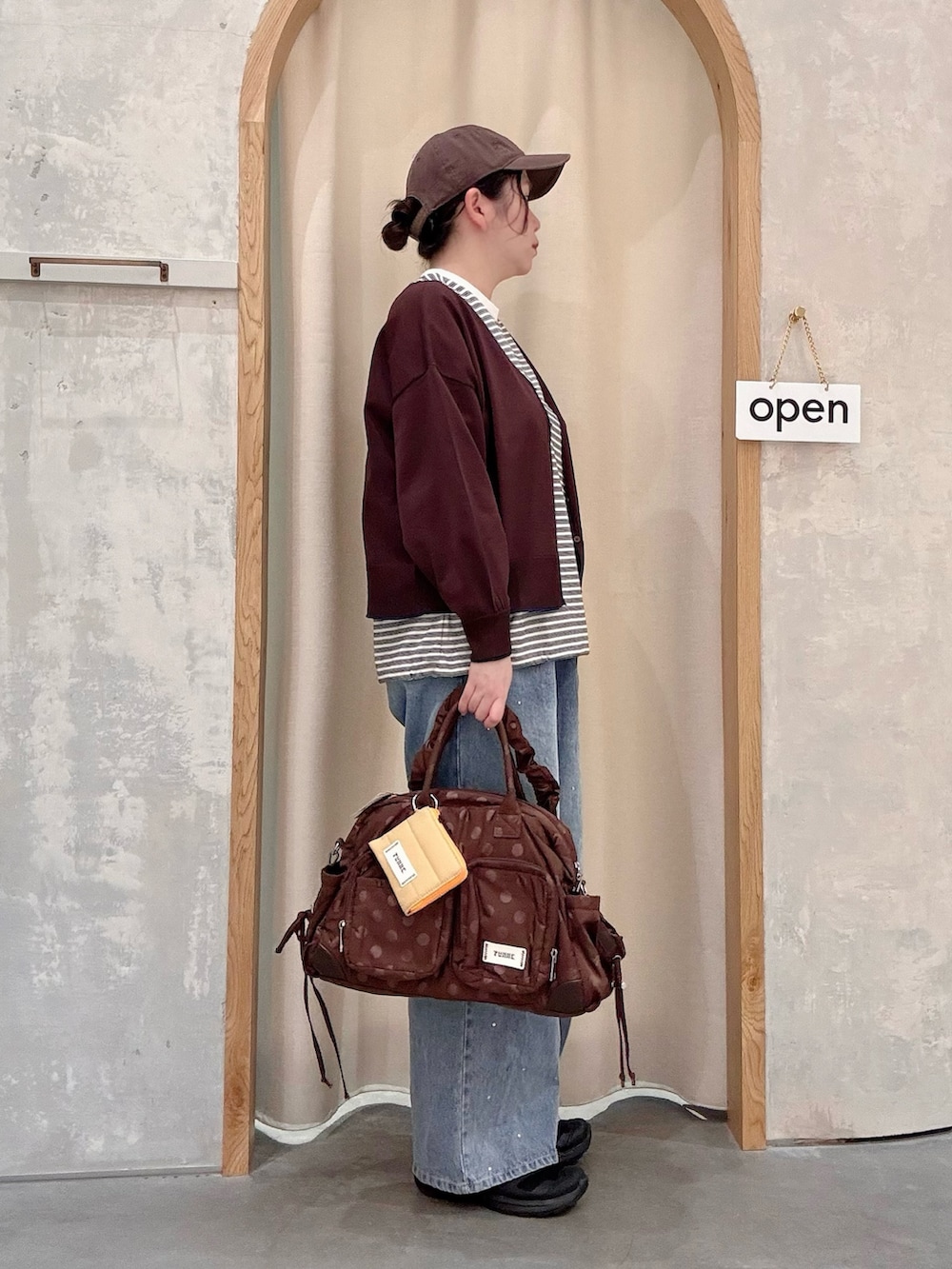 ブルー系のデニムパンツ、ブラウン系のカーディガン/ボレロ、ホワイト系のTシャツ/カットソーを着用したレディースの秋コーディネートの2枚目の写真