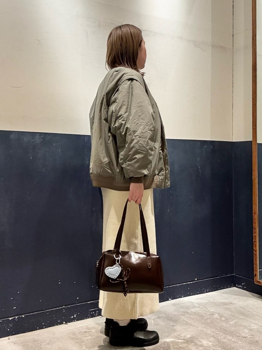 ホワイト系のスカート、ブラウン系のトートバッグ、ホワイト系のニット/セーターを着用したレディースの冬コーディネートの2枚目の写真