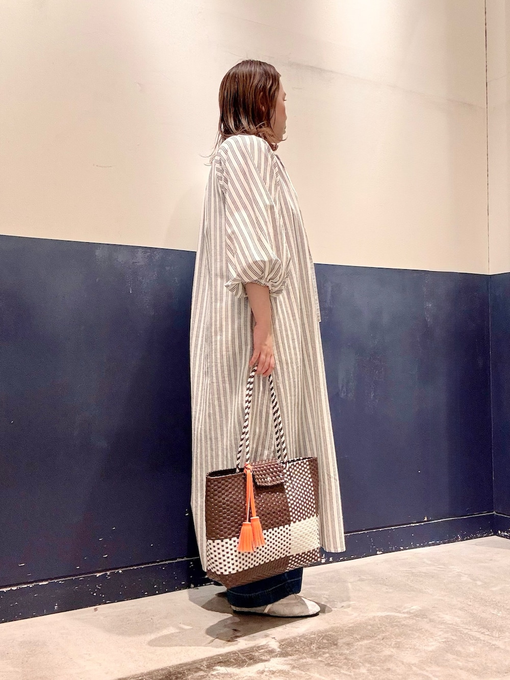 ホワイト系のパンプス、ブルー系のデニムパンツ、ブラウン系のトートバッグを着用したレディースの夏コーディネートの2枚目の写真