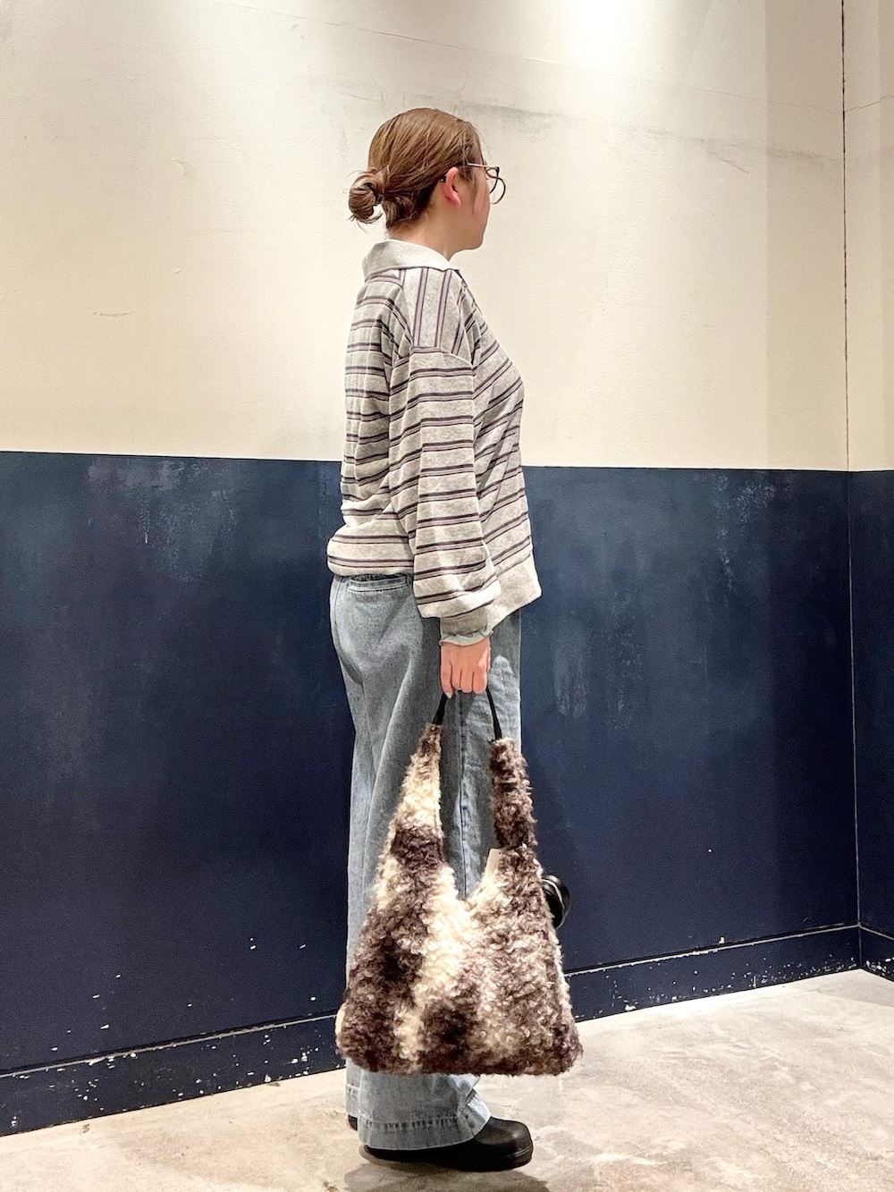 グレー系のトートバッグ、ブルー系のTシャツ/カットソー、ブルー系のデニムパンツを着用したレディースの冬コーディネートの2枚目の写真