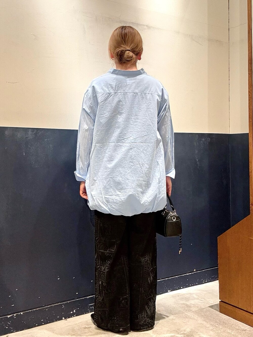 ブラック系のパンプス、ブルー系のシャツ/ブラウス、ブラック系のショルダーバッグを着用したレディースの春コーディネートの3枚目の写真